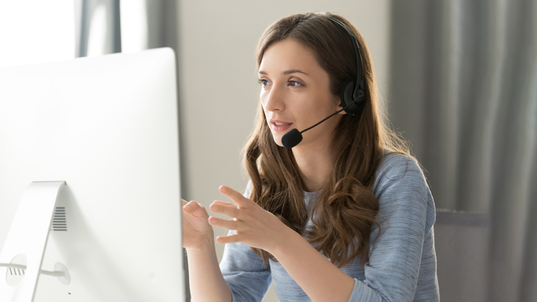 woman in headphones with microphone consulting client on phone